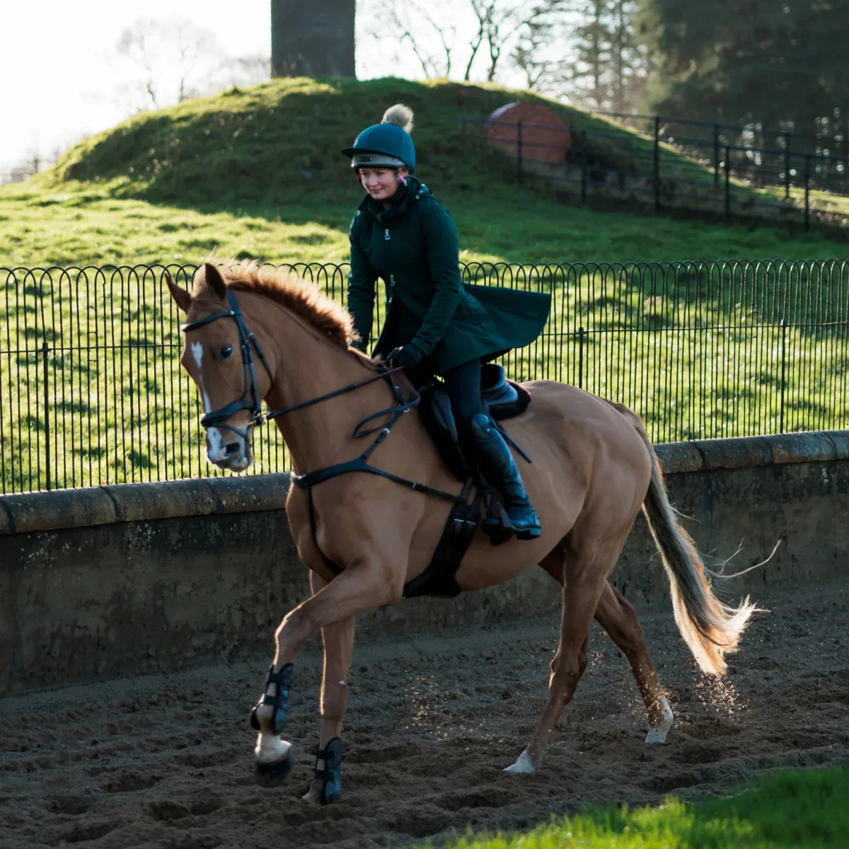 Equestrian rider on a chestnut horse wearing an EcoRider anatomical leather bridle and matching elasticated breastplate in an outdoor arena.